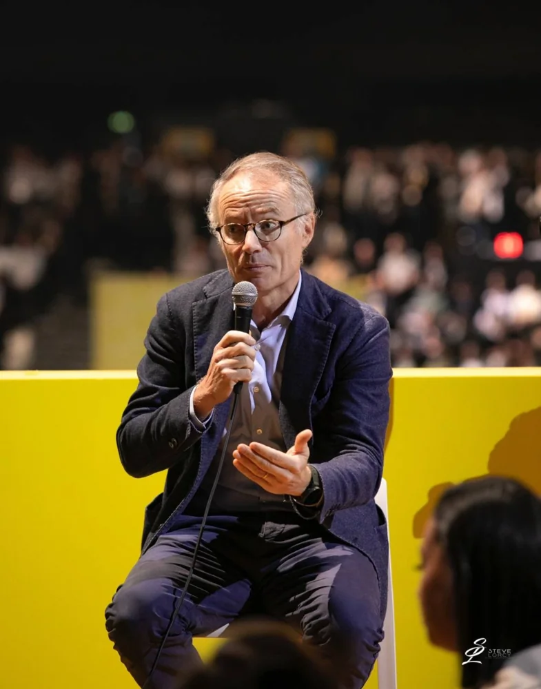 Intervenant avec un microphone sur fond jaune